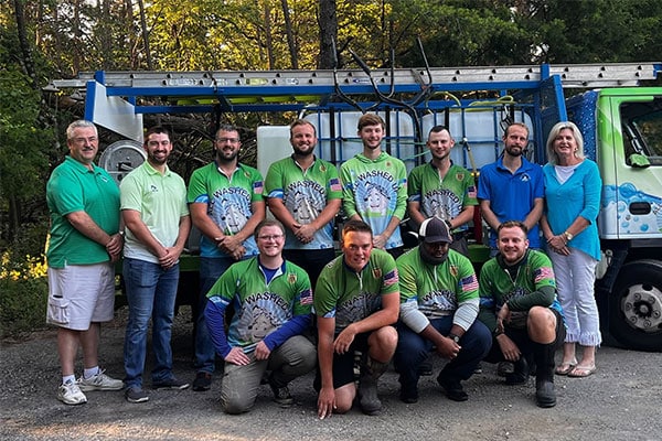 A group of diverse men and one woman, representing potential careers, pose in front of a green truck with "Washed Up" logo. Some wear matching green shirts with an American flag patch, while others wear solid green or blue shirts.